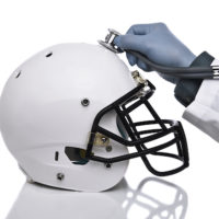 Doctor holds stethoscope to football helmet
