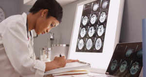 Doctor taking notes from brain x-ray