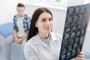 Doctor looking at x-ray photo with patient in background