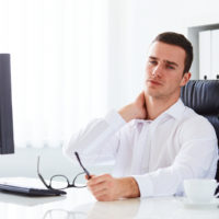 Young businessman with neck pain at work