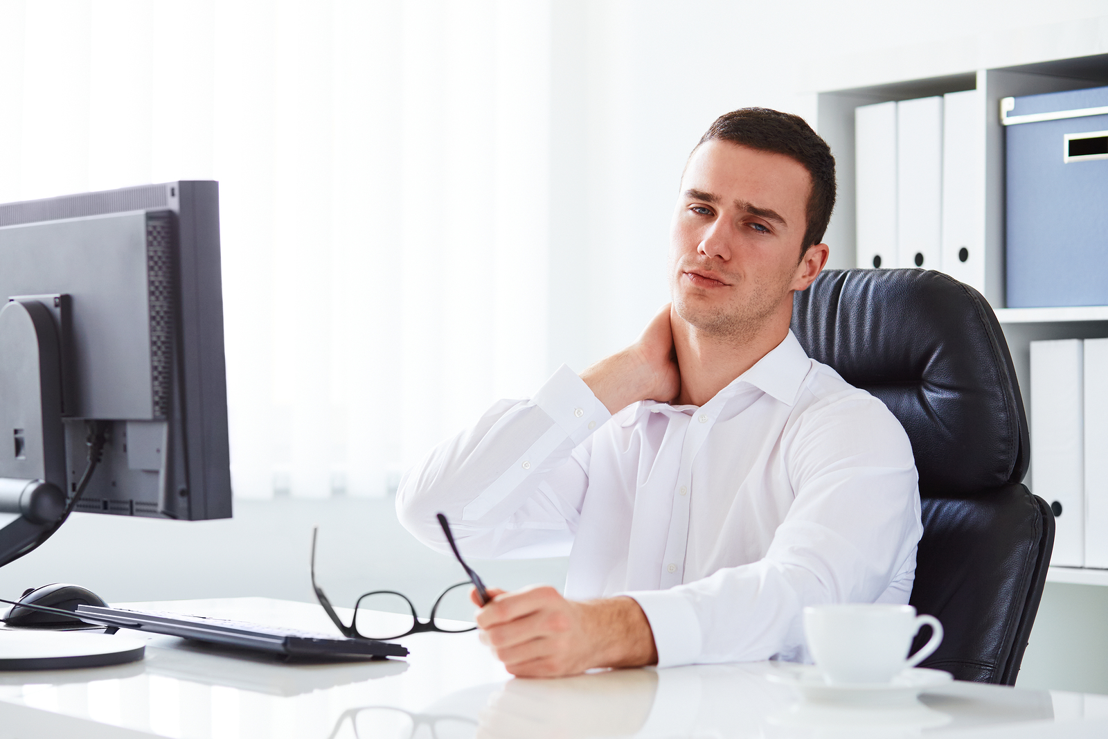 Young businessman with neck pain at work