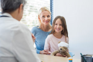 Mother and smiling daughter in doctor's office