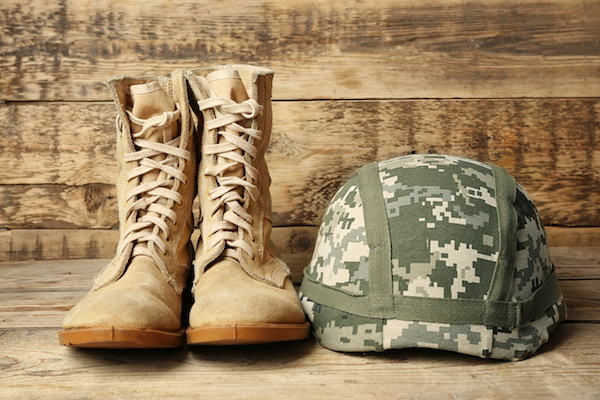 Pair of combat boots and military helmet on wooden background, close up
