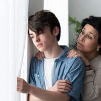 teen boy and concerned mom at window