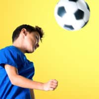 child hitting soccer ball with head