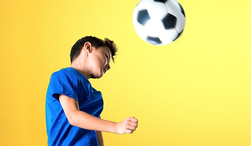 child hitting soccer ball with head